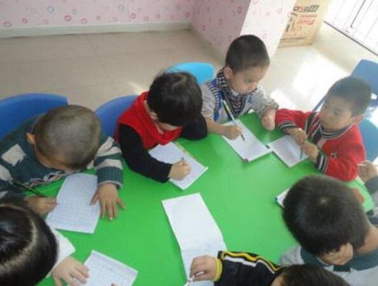 初学握笔写字的幼儿园小朋友